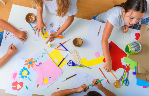 Kids creating art with cut paper and other supplies