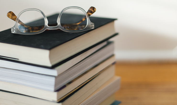Stack of books with a pair of reading glasses placed on top